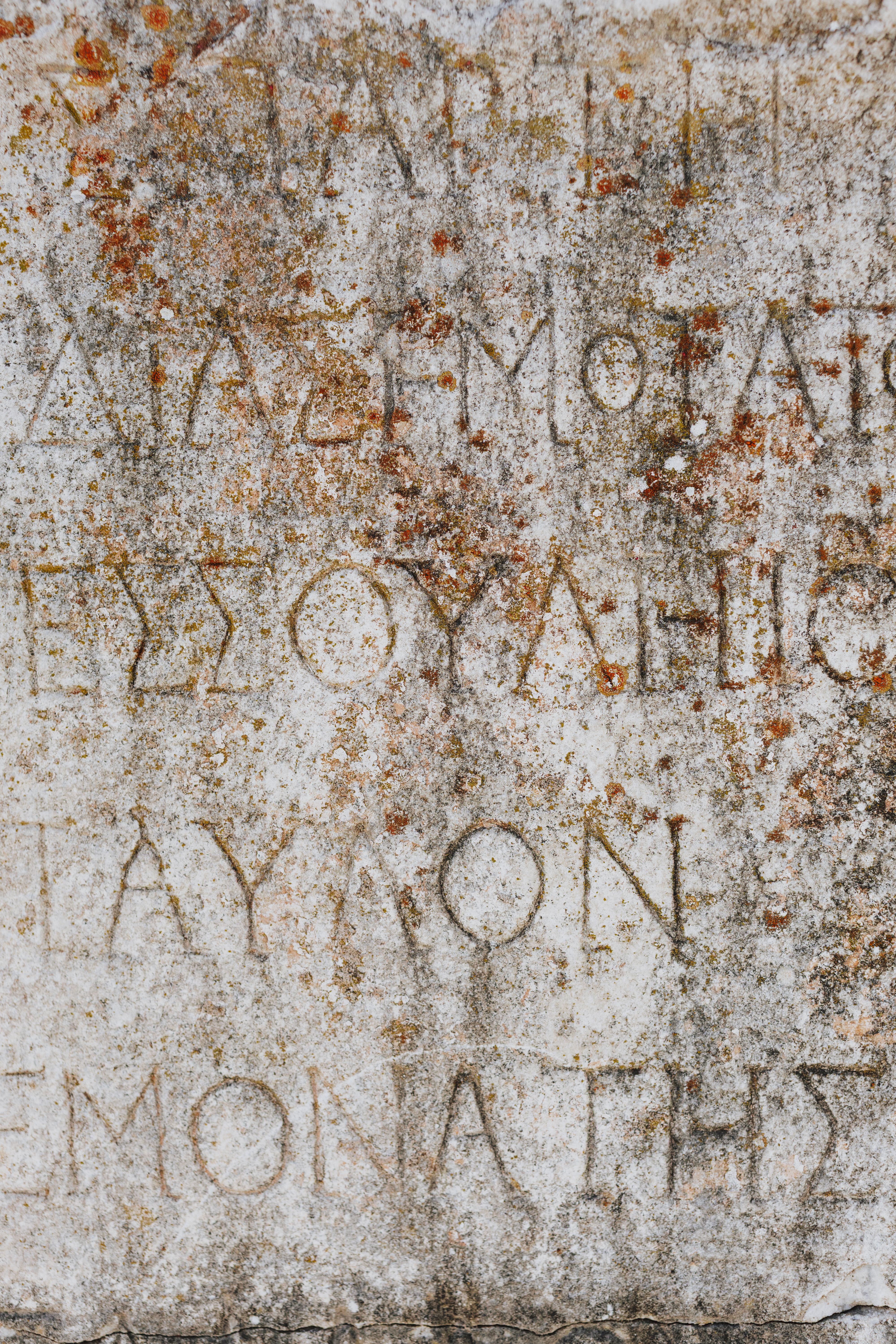 Close-up of ancient Greek inscription on a weathered stone surface in Izmir, Turkey.