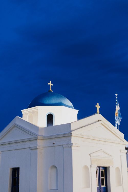 Free Traditional white Greek church with a blue dome against a vibrant twilight sky in Greece. Stock Photo