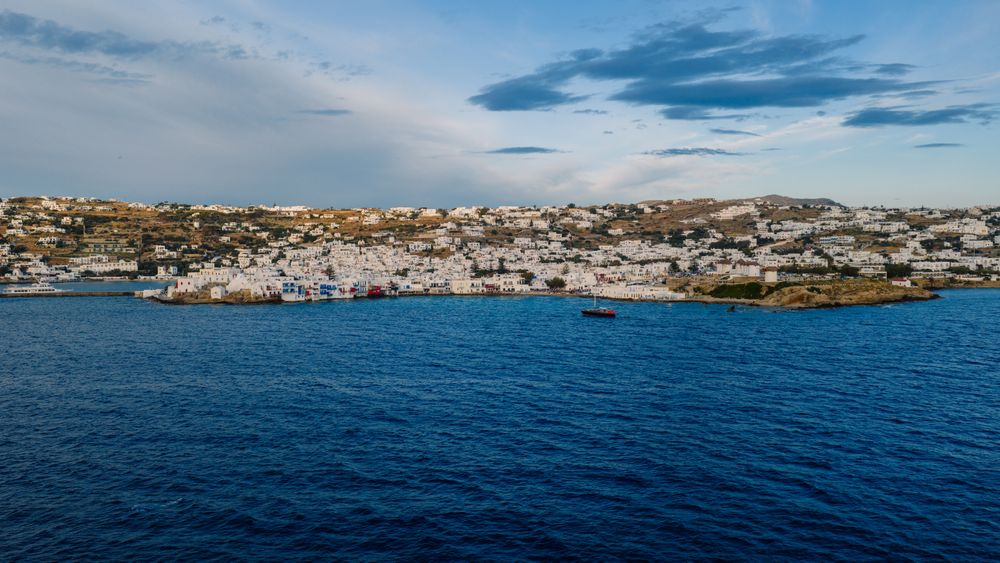 Whitewashed Mykonos town seen from the sea under a wide sky