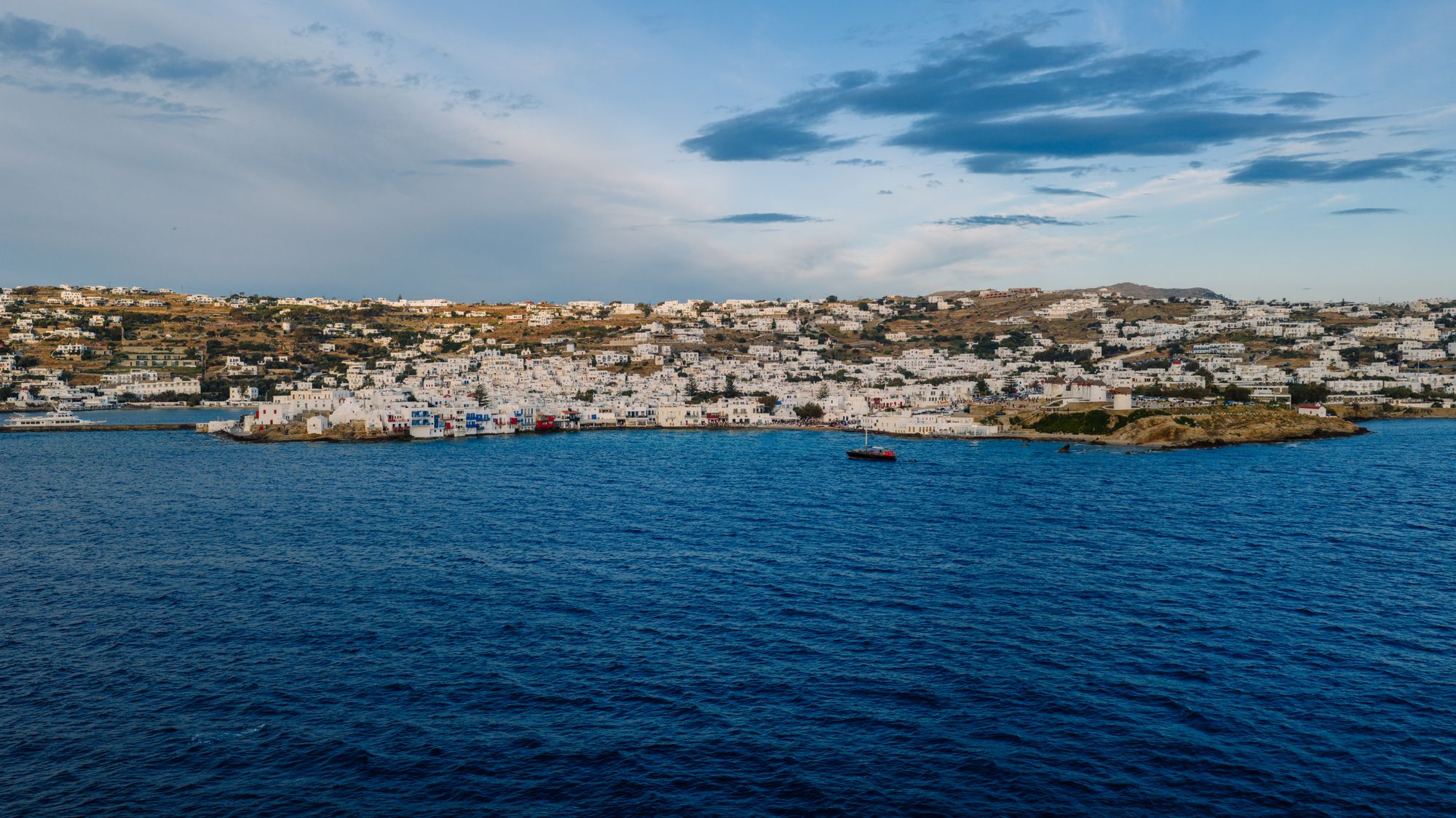 Whitewashed Mykonos town seen from the sea under a wide sky