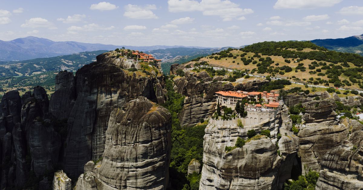 Stunning aerial shot of Meteora monasteries perched on rocky cliffs in Greece's landscape.