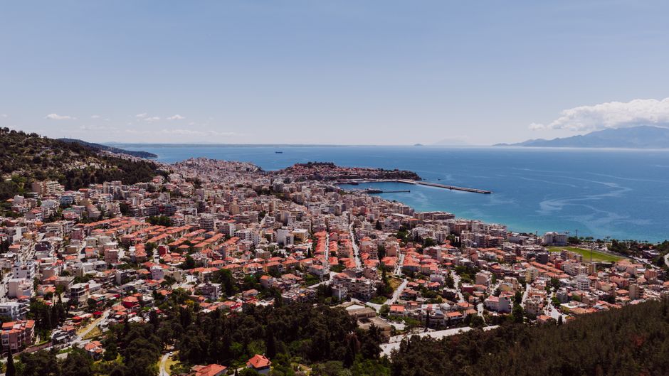 Stunning Private Helicopter Transfer from Athens to Costa Navarino Review 2026 - Stunning aerial view of Kavala, Greece, with vivid cityscape and blue Aegean Sea, captured under a clear summer sky.