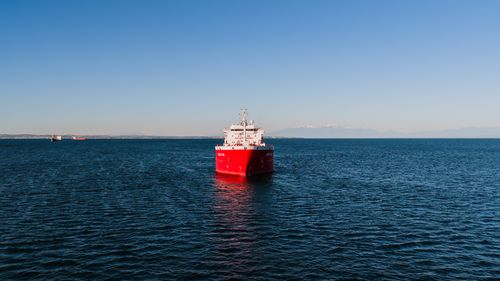 Free Red cargo ship navigating the serene waters of Thessaloniki, Greece. Stock Photo