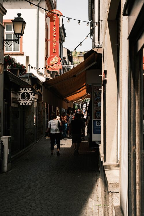 Free Explore a vibrant alleyway in Rüdesheim, Germany featuring outdoor seating and bustling cafe culture. Stock Photo
