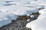 白雪覆盖着岩石景观，部分冰冻的溪流蜿蜒流过