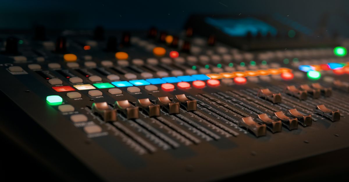 A mixing console with faders and a glowing red