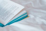 白色面料上，一本打开的书以绿松石色边缘为特写，非常适合教育或文学主题