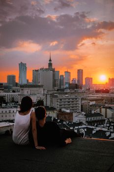 Couple enjoying a stunning Warsaw sunset from a rooftop, capturing a romantic moment overlooking the cityscape.