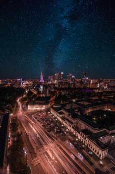 Spectacular nighttime aerial view of a cityscape under a starry sky with urban lights aglow.