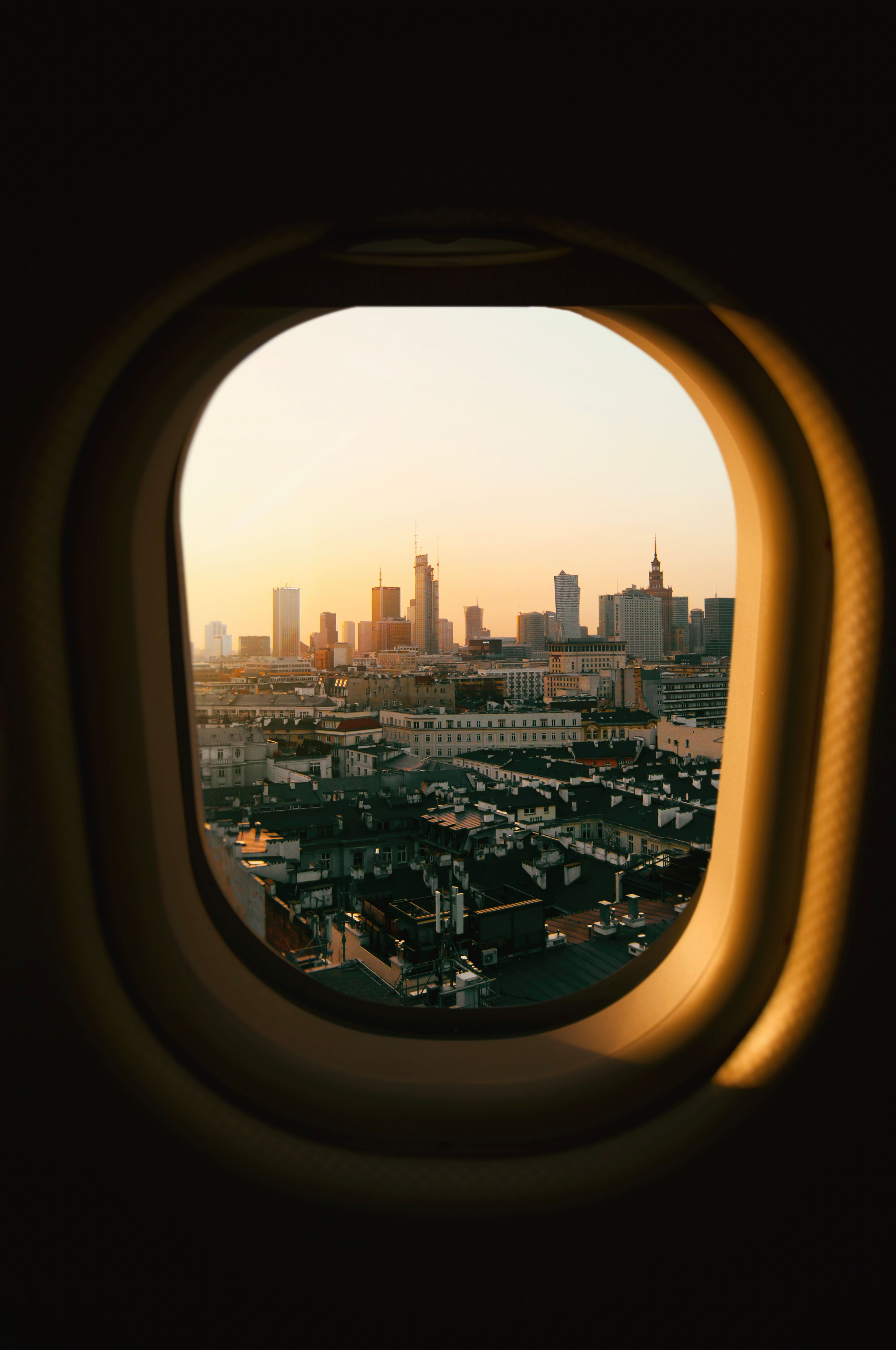 View of Warsaw's skyline at sunset through an airplane window, capturing urban beauty.