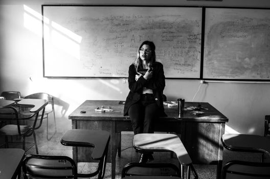 A thoughtful moment captured in a university classroom featuring a lecturer sitting on a desk, Buenos Aires.