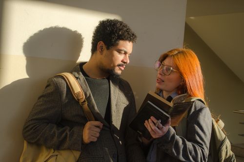 Free Two university students engaged in a discussion while reading a book inside a building in Buenos Aires, Argentina. Stock Photo