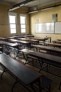 Sunlit empty classroom in Buenos Aires with rows of desks and a whiteboard.