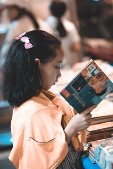 一位专注的年轻女孩正在室内阅读一本色彩缤纷的书，非常适合教育主题