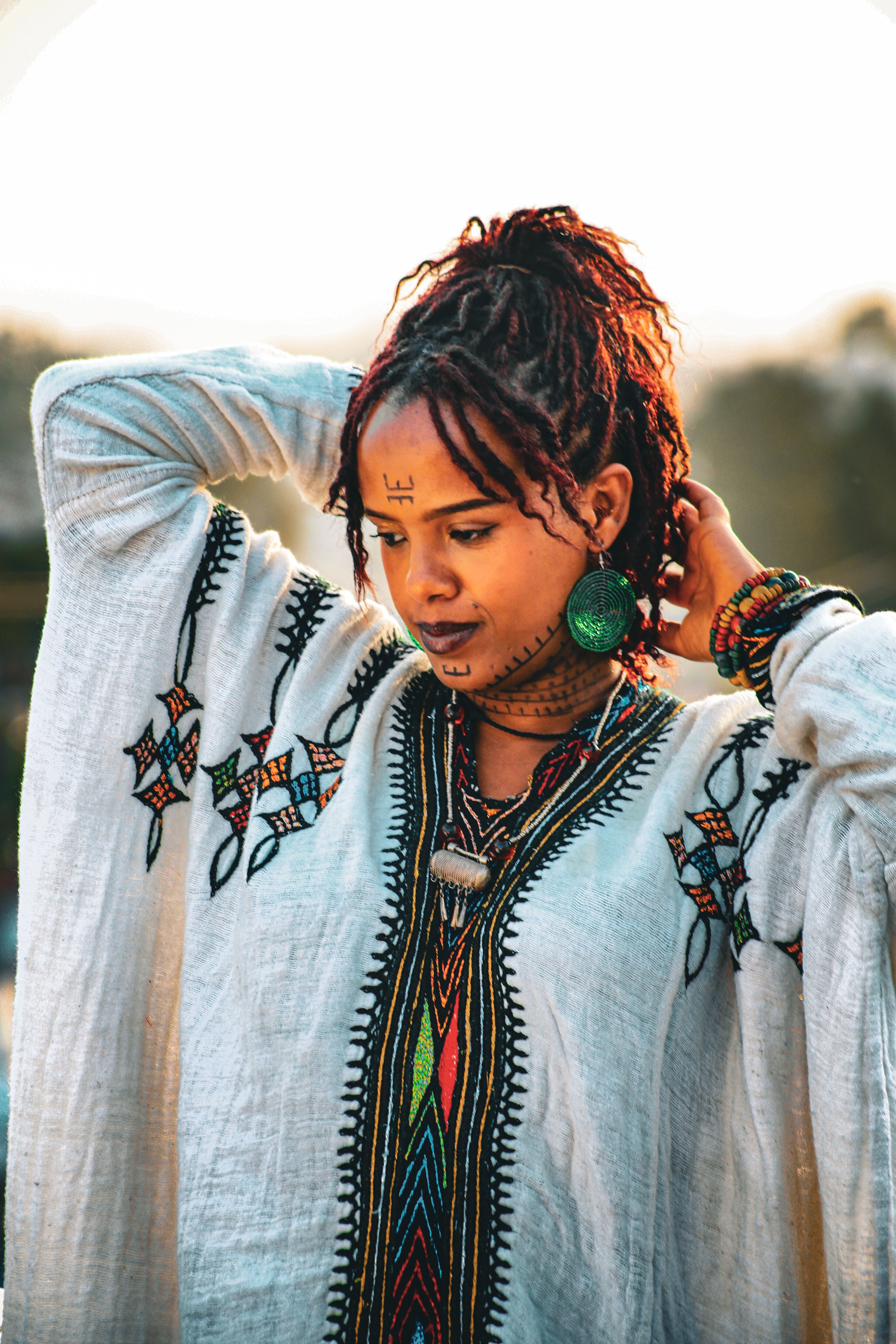 Woman in traditional Ethiopian dress with cultural face markings, captured at sunset in Addis Ababa.