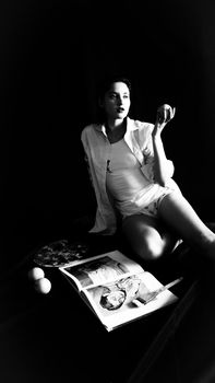 Artistic black and white photo of a woman in a relaxed and stylish pose with magazines.