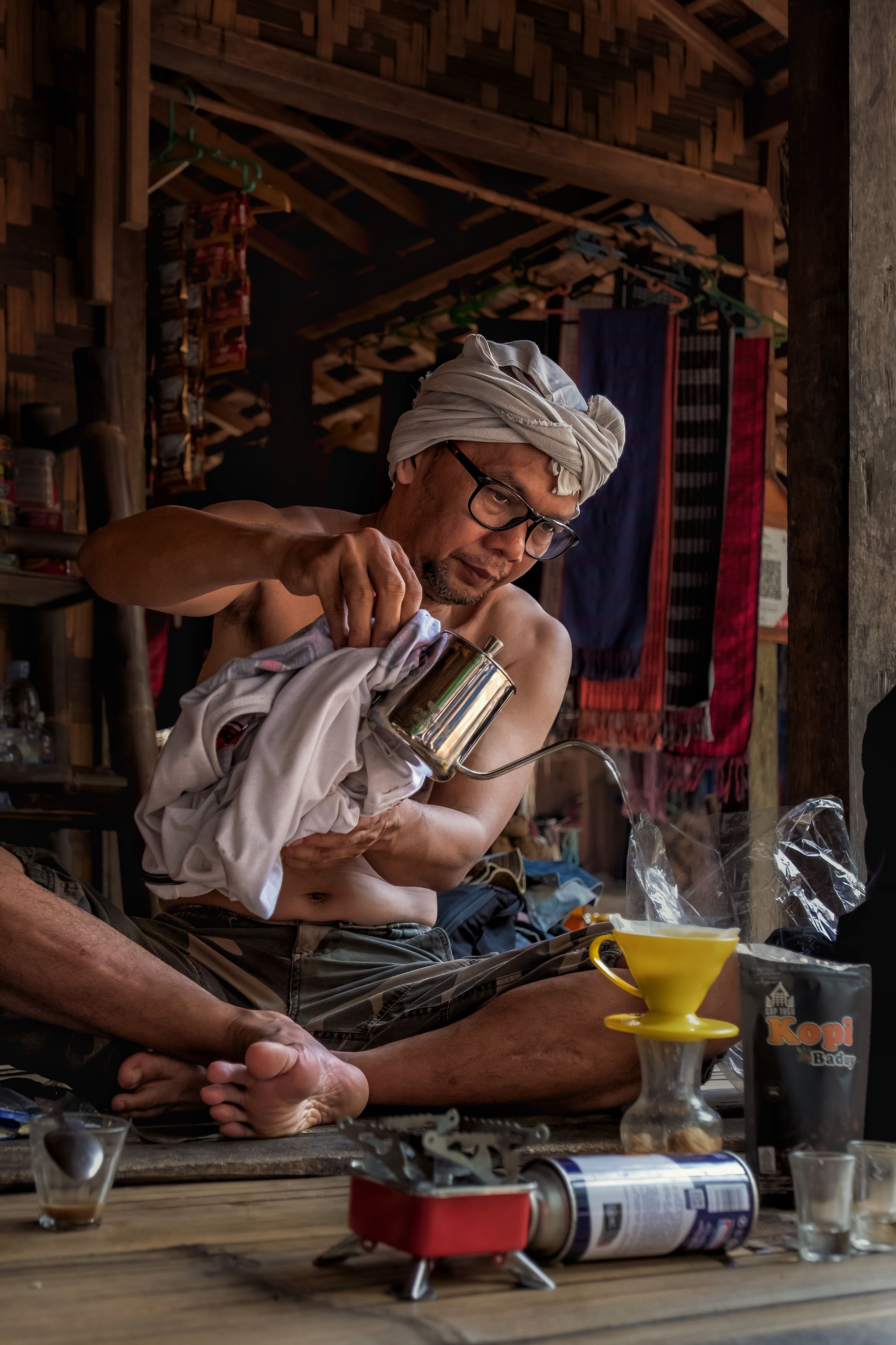 A man brewing coffee in a traditional setting with rustic decor, highlighting cultural craftsmanship.
