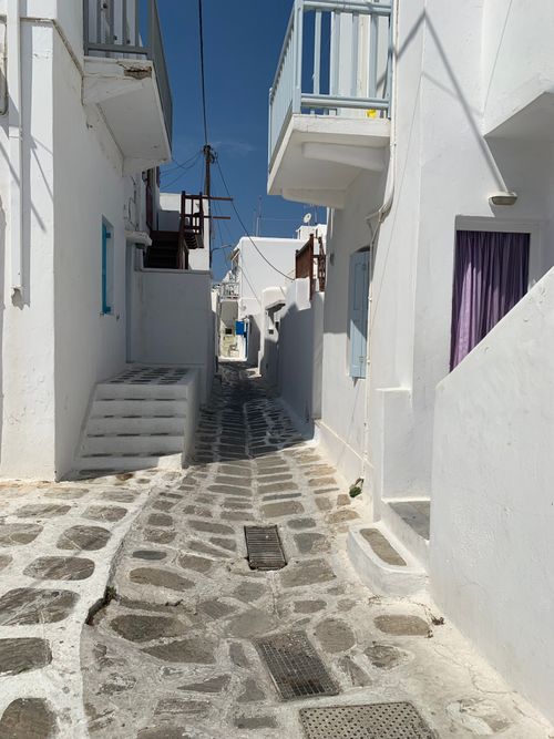 Free Charming narrow alley in Mykonos with iconic white Cycladic architecture under blue skies. Stock Photo