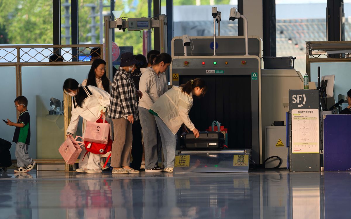Travelers undergo security screening at an airport terminal.