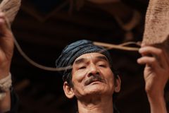 A close-up of an elderly Indonesian craftsman weaving a traditional basket, showcasing cultural heritage.