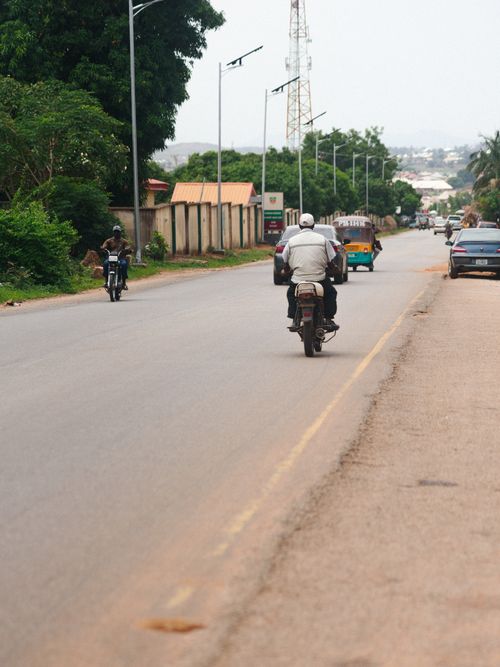 Free Two motorcyclists and a rickshaw on a road in Jos, Nigeria, showcasing daily commute. Stock Photo