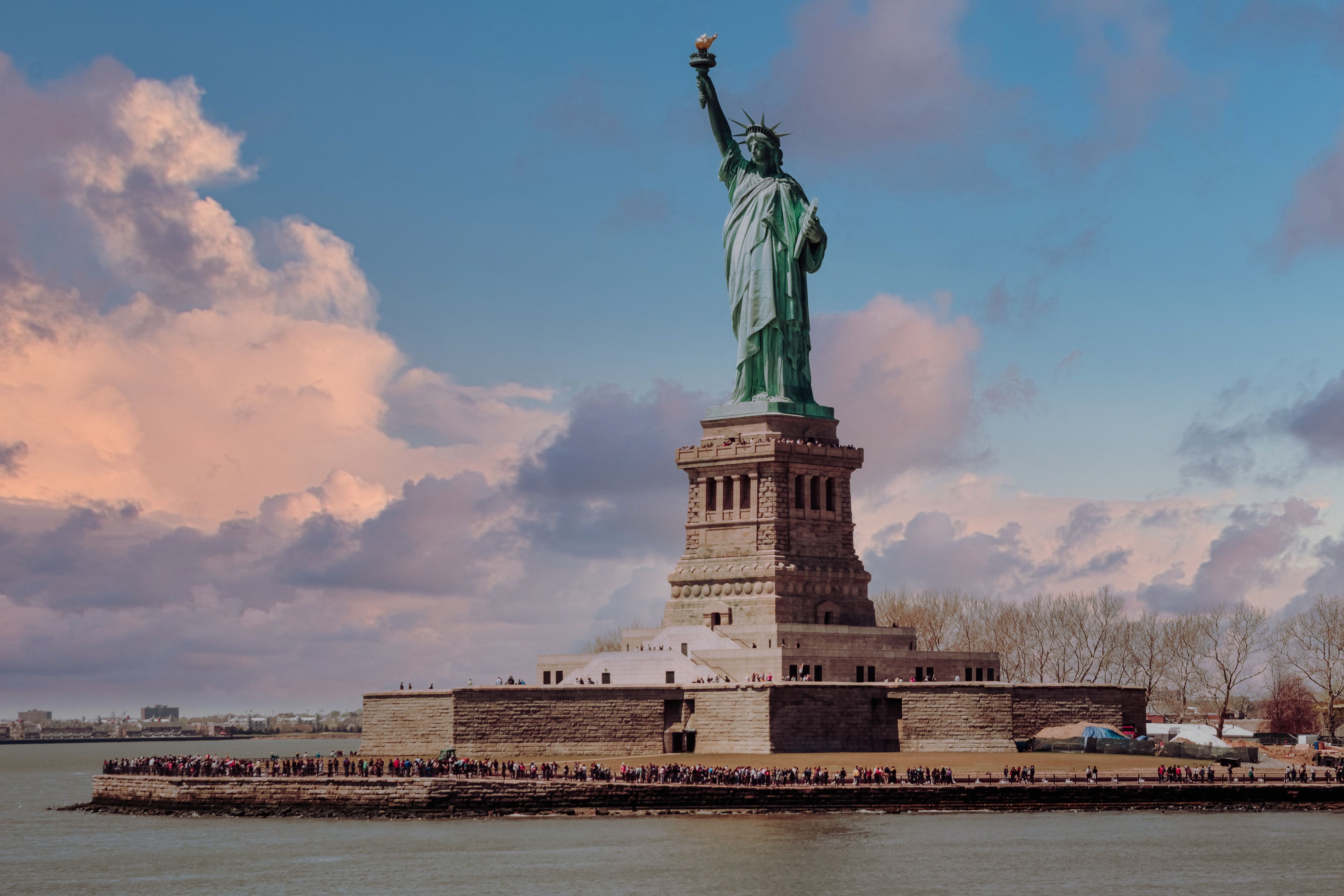 Captivating view of the Statue of Liberty with a vibrant sunset in New York City, USA.