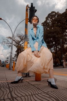 Fashionable woman in eclectic outfit poses confidently on an urban sidewalk.