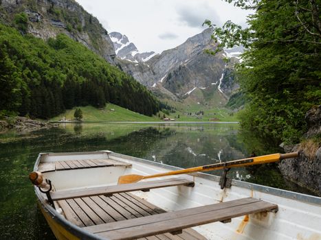 Tranquil scene of a rowboat on a serene alpine lake in Schwende-Rüte, Switzerland.