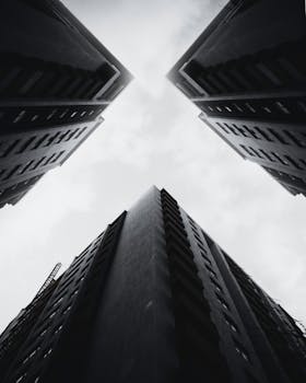 低角度视角下，高耸的摩天大楼与多云天空交汇，展现出现代建筑的魅力