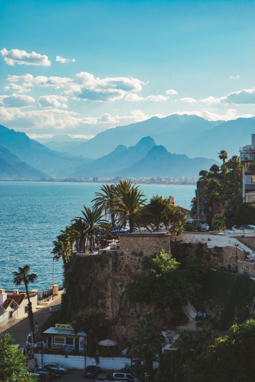 Free Breathtaking view of Antalya's coastline with palm trees and majestic mountains under a blue sky. Stock Photo