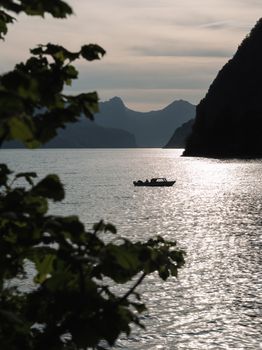 A serene boat ride on a Swiss lake with a mountain backdrop during sunset.