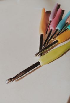 A set of colorful crochet hooks arranged artistically on a neutral surface, perfect for craft enthusiasts.