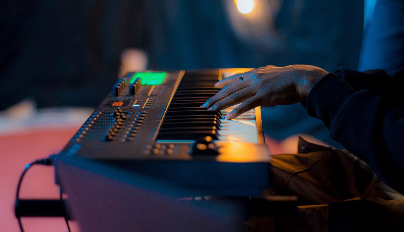 A hand playing an electronic keyboard in warm light — photo by Jeith Photography on Pexels