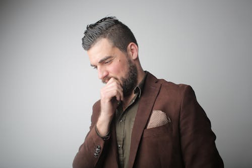 Free Pensive Man in Brown Coat Holding His Chin Stock Photo