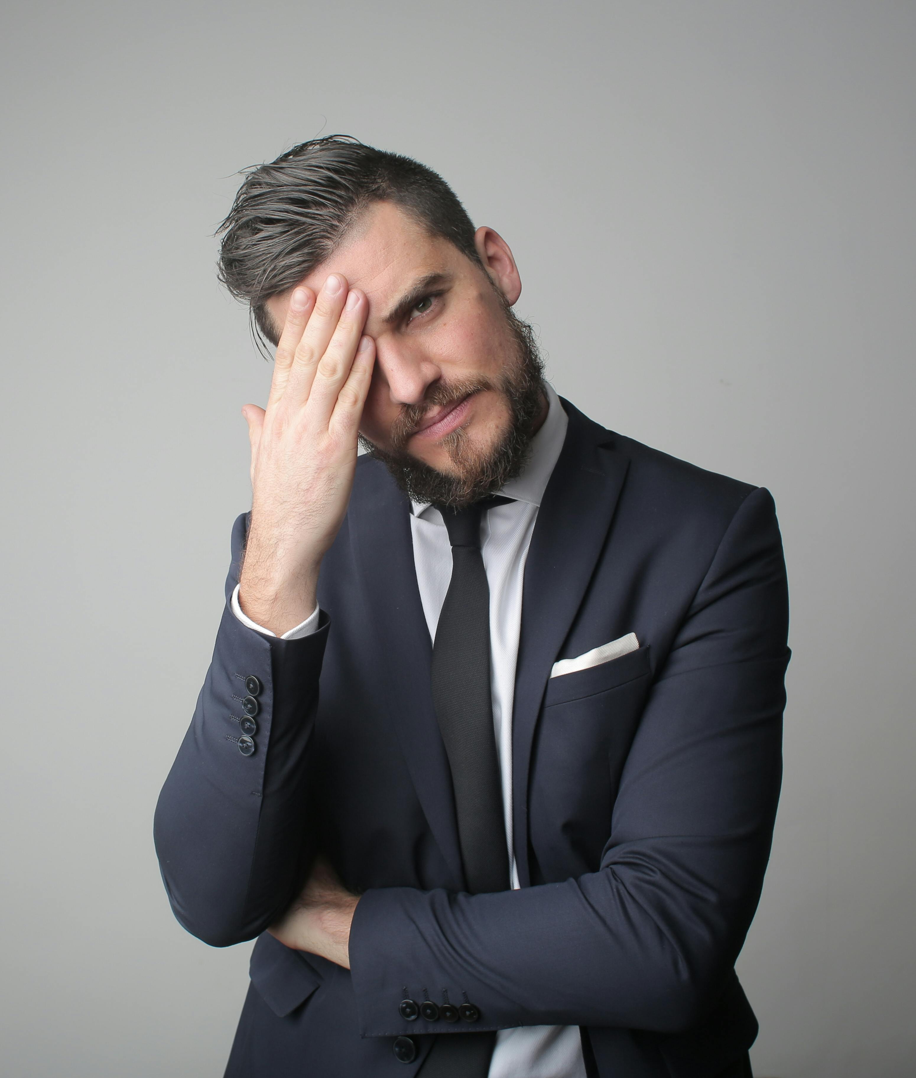 Man in black suit jacket touching his face. | Photo: Pexels