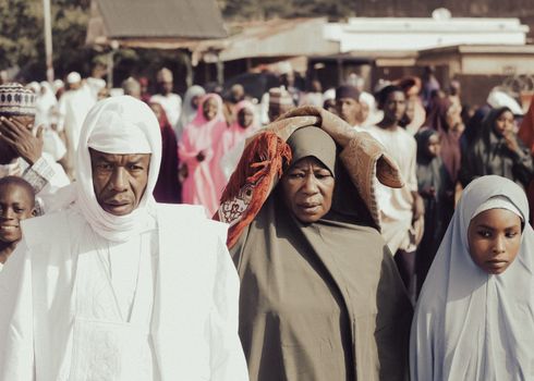 A diverse group of people in traditional garments during a day event in an outdoor setting.