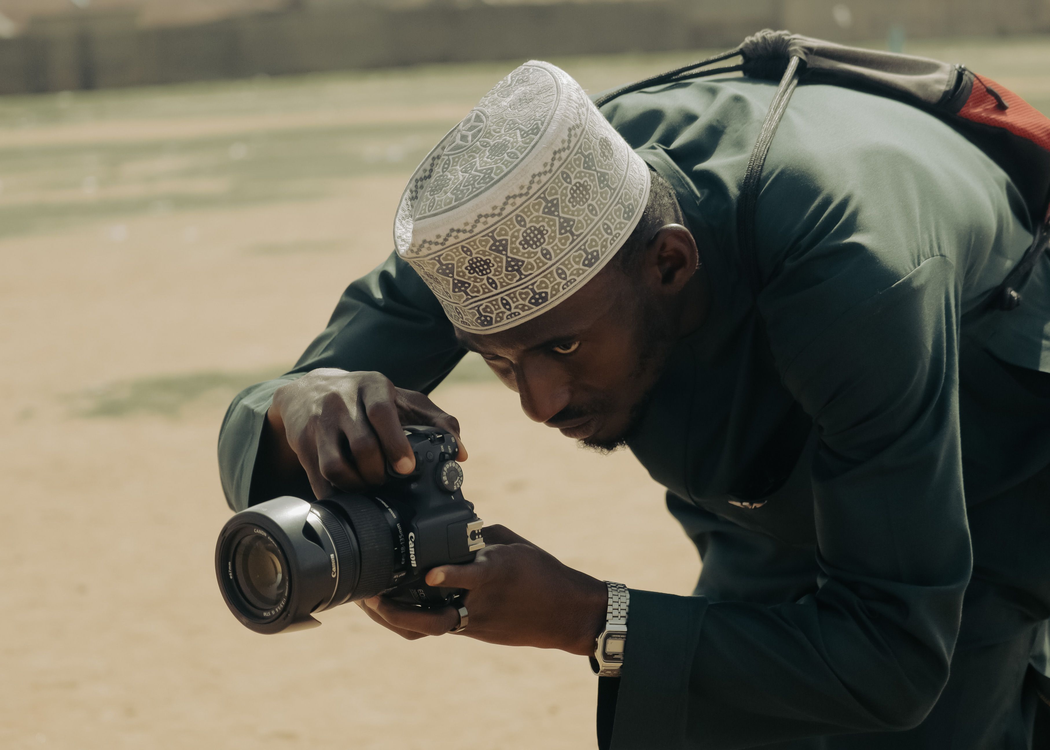A dedicated photographer wearing traditional attire captures the perfect shot outdoors.