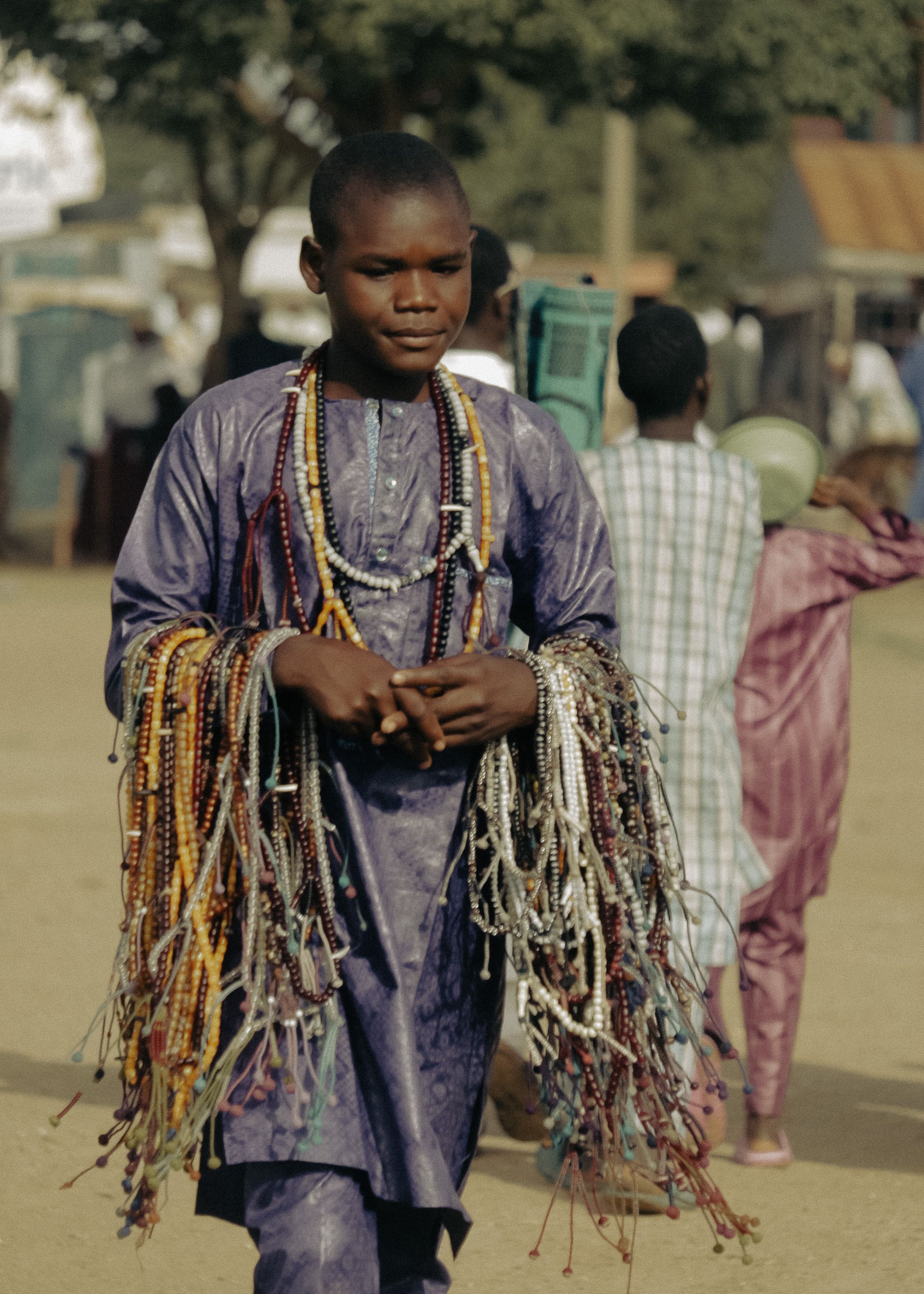Un jeune vendeur présente ses colliers artisanaux au marché