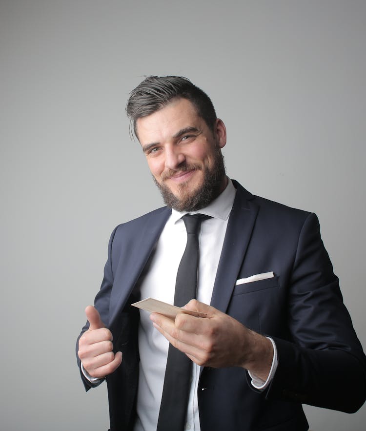 Man In Black Suit Holding A Calling Card