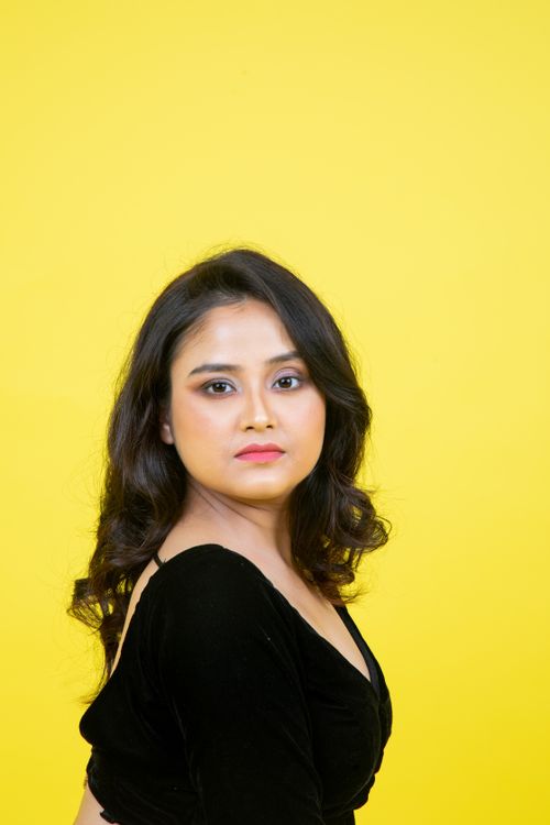 Free Elegant portrait of a woman in black attire set against a vivid yellow backdrop. Stock Photo