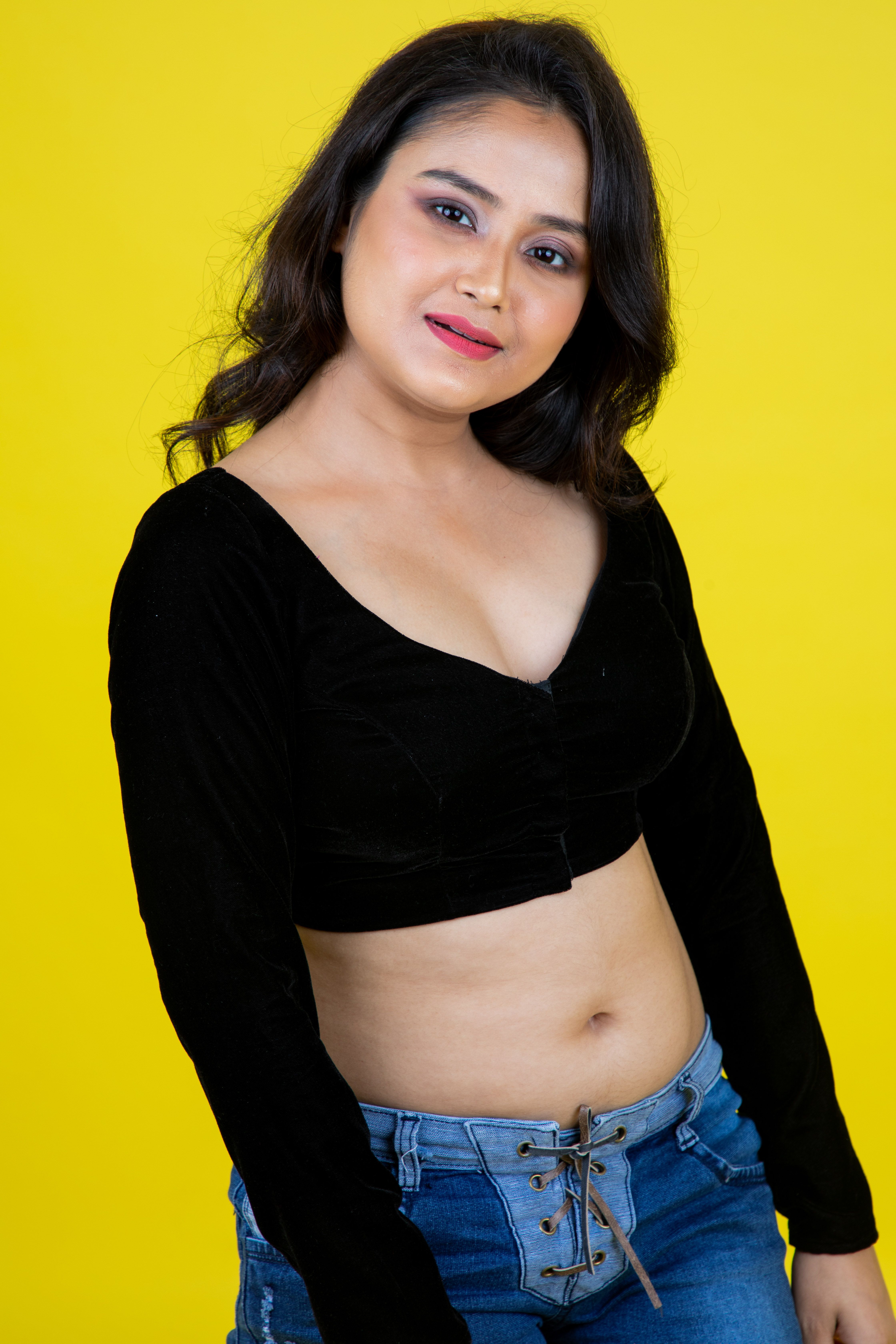 Fashionable woman poses against a vibrant yellow background.