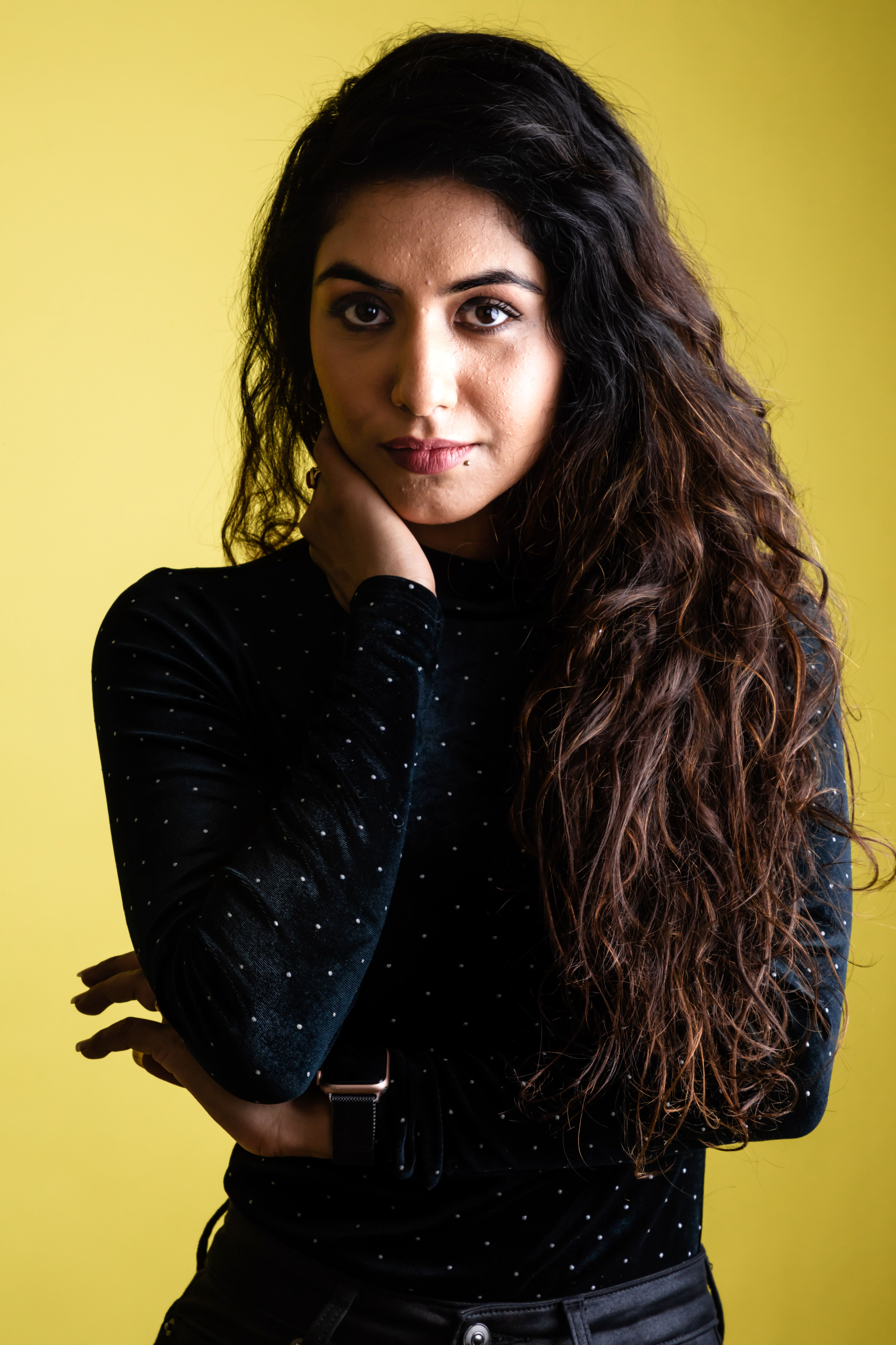 Striking portrait of a woman in black attire against a yellow background.