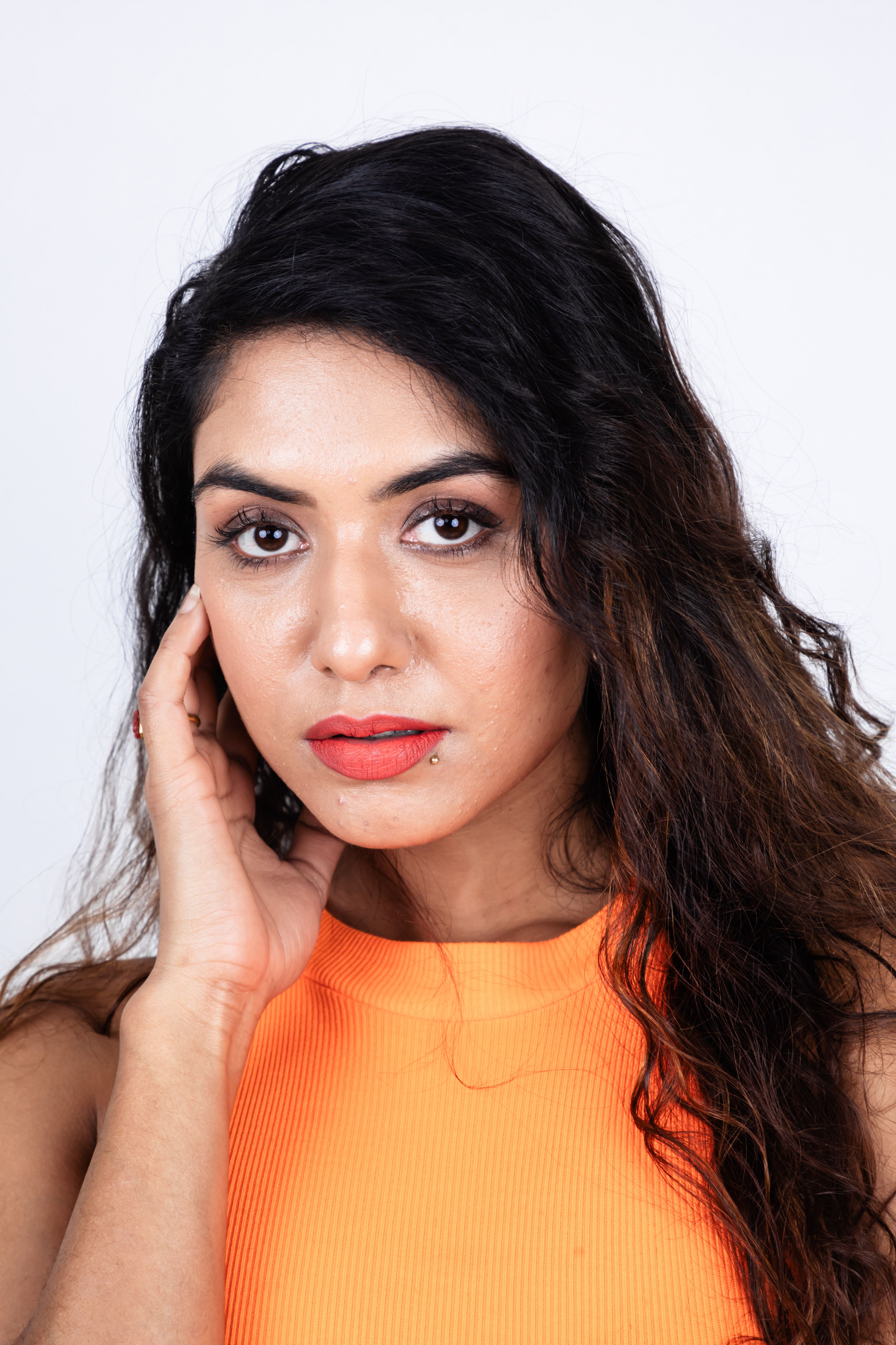 Portrait of a Woman in Orange Tank Top with Hand on Face · Free Stock Photo