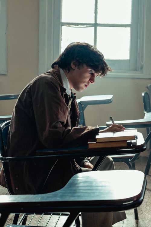 Free Focused student writing in classroom notebook by window light. Stock Photo