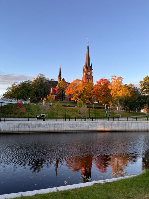 Free A picturesque view of Härnösand Cathedral with vivid autumn colors reflecting in the water. Stock Photo