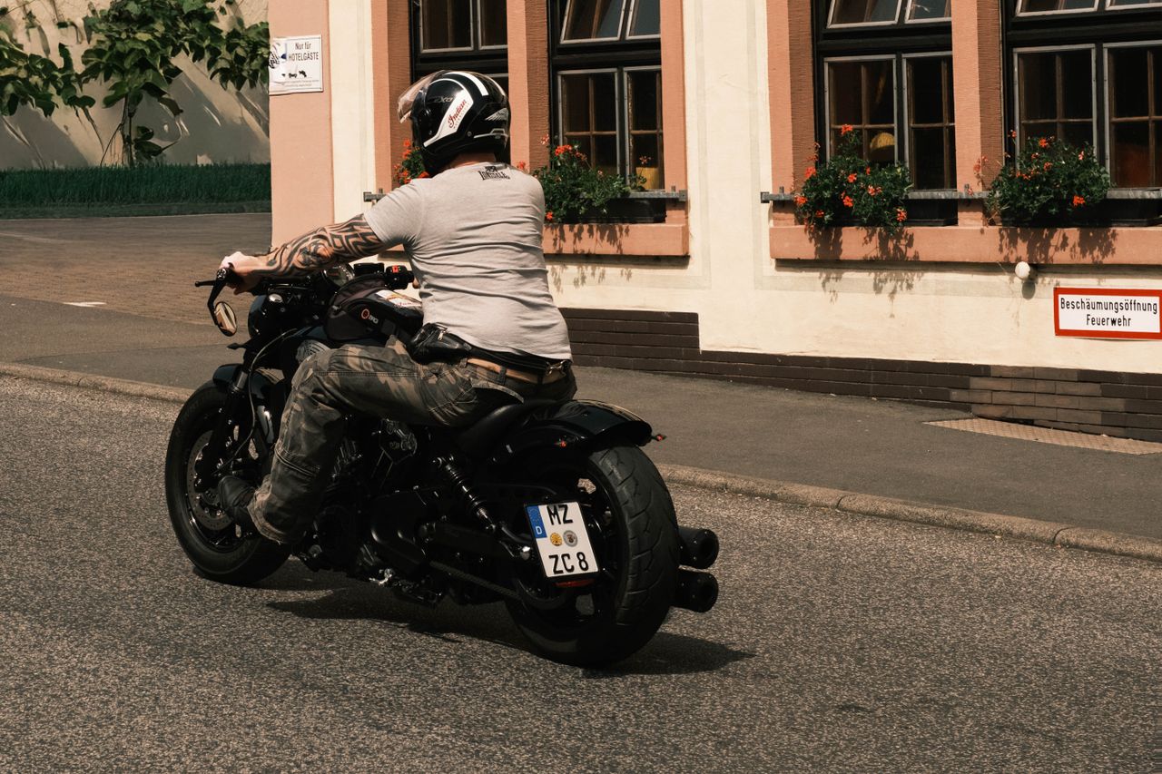 a motorcyclist rides past a traditional german building on a sunny day