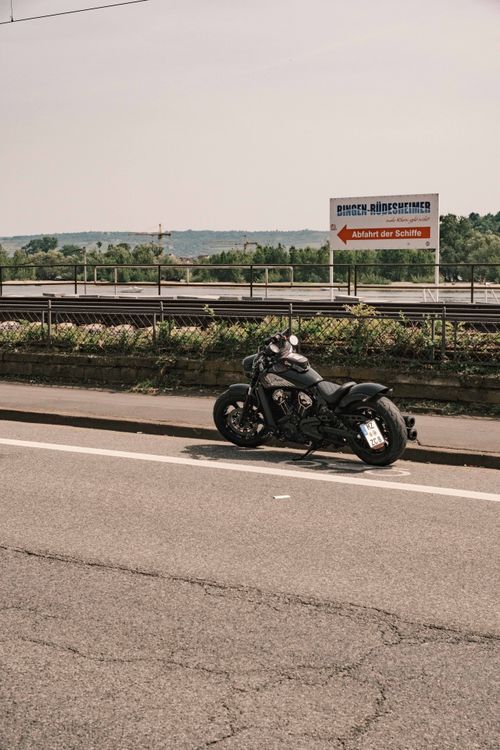 Free A parked cruiser motorcycle on the roadside by a scenic riverbank on a summer day. Stock Photo