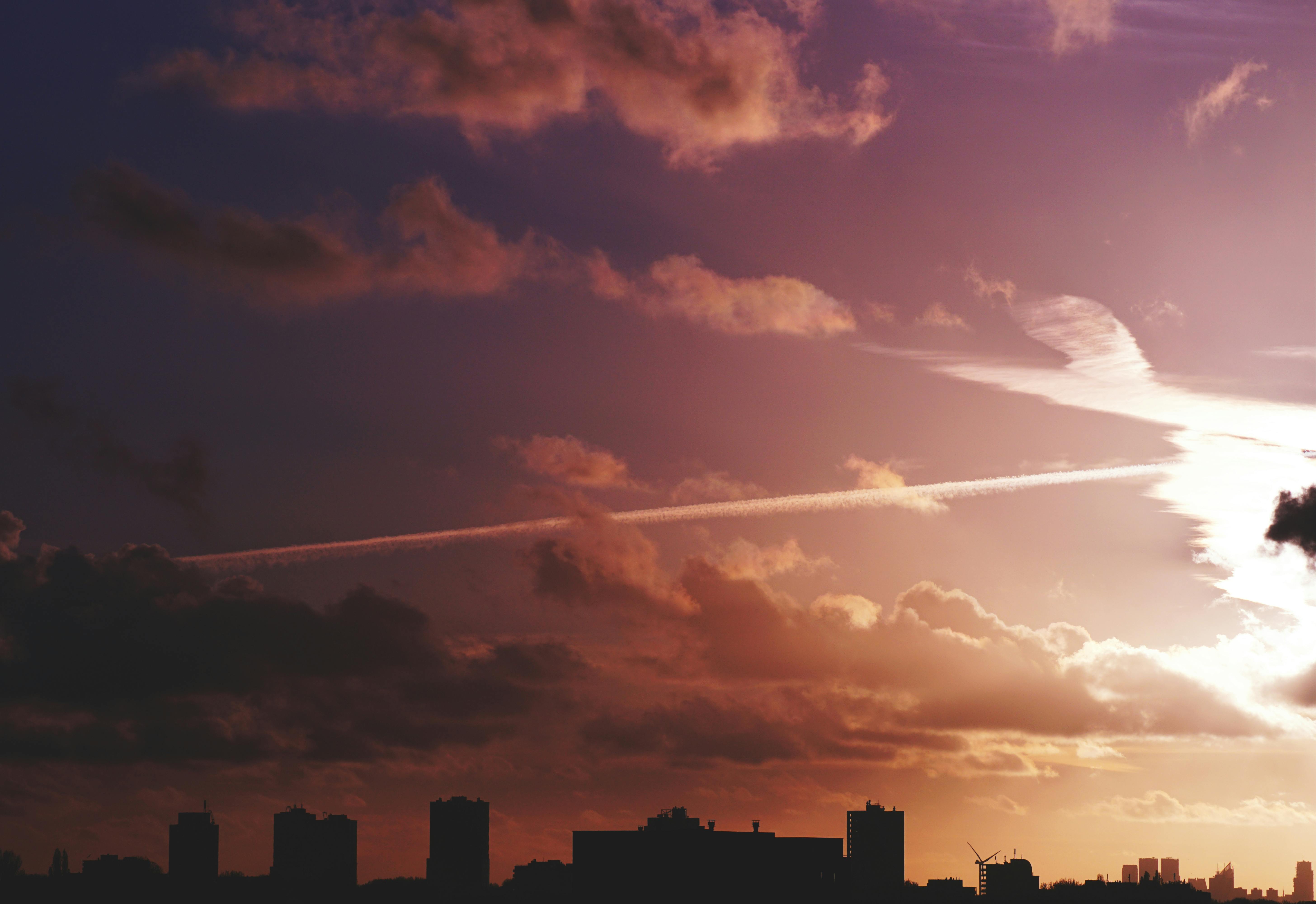 城市天际线的剪影映衬着戏剧性的日落天空，云层和轨迹点缀其间