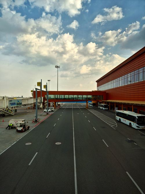Free A bustling airport tarmac with terminal and buses under a cloudy sky. Stock Photo