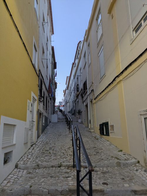Free Explore a picturesque cobblestone alleyway in Sesimbra, showcasing traditional Portuguese architecture. Stock Photo